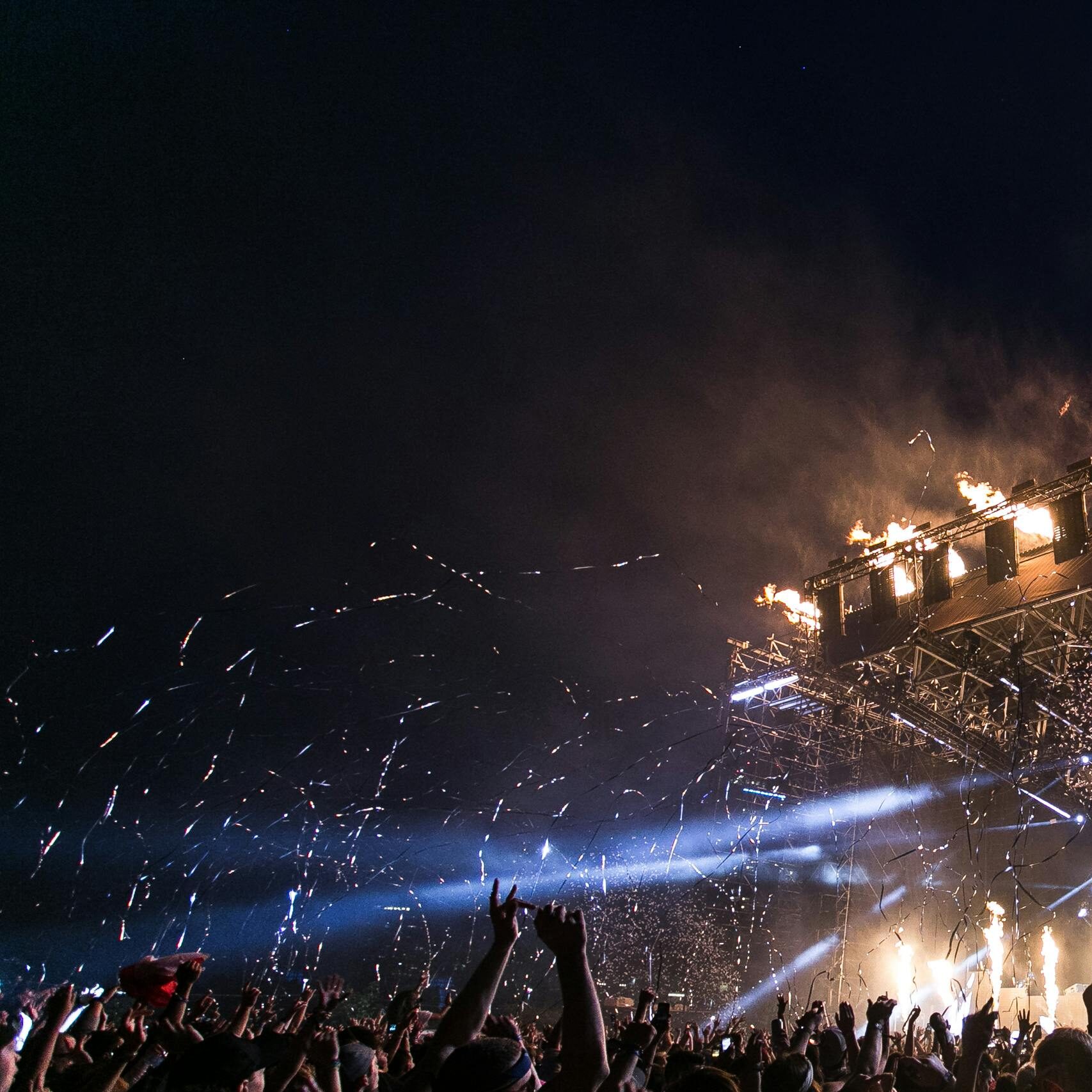Vibrant concert scene with crowd enjoying night festival and dynamic stage fireworks.